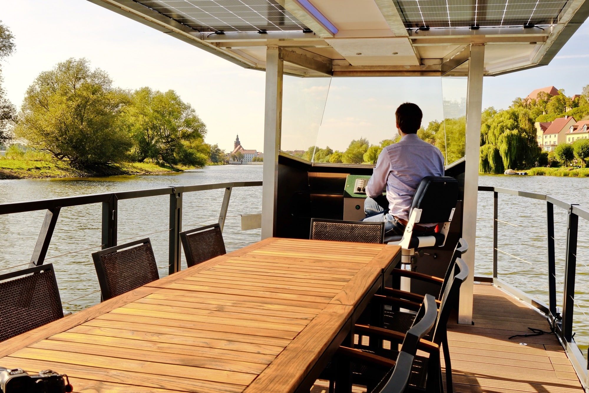 Steuerstand des Solar-Charterboots PonTOM Empor 9.0 mit großem Holztisch und Blick über die Havel