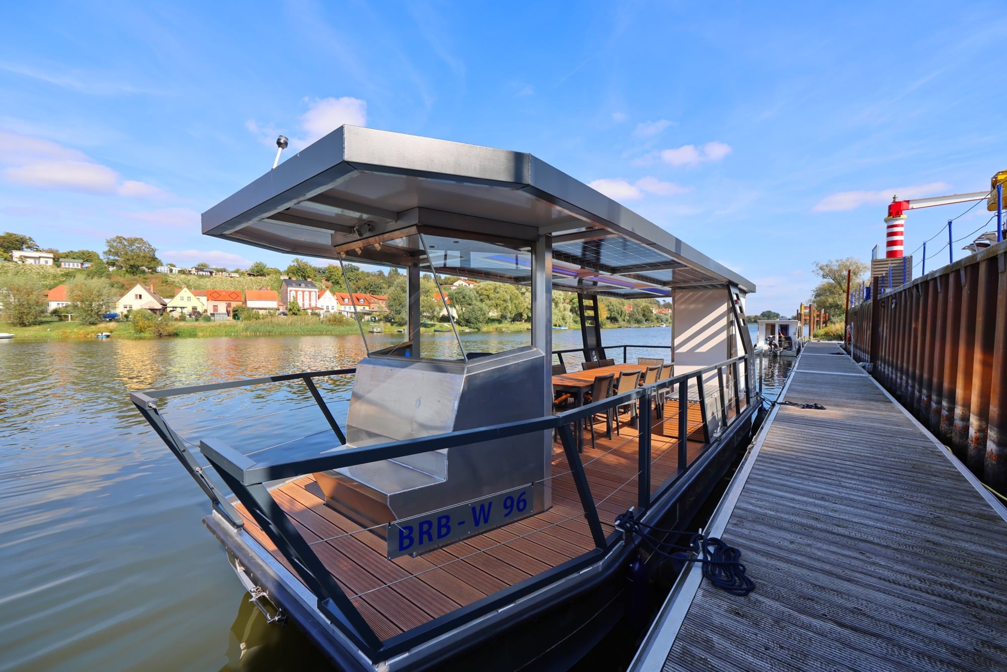 Solar-Charterboot PonTOM Empor 9.0 am Holzsteg in Havelberg, im Hintergrund Häuser, Leuchtturm und Havelufer