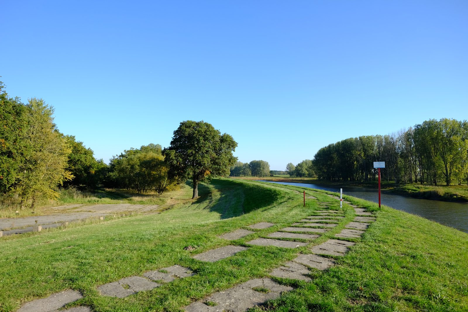 Grasbewachsener Deichweg entlang eines ruhigen Flusslaufs in der Elbe-Havel-Landschaft bei Havelberg