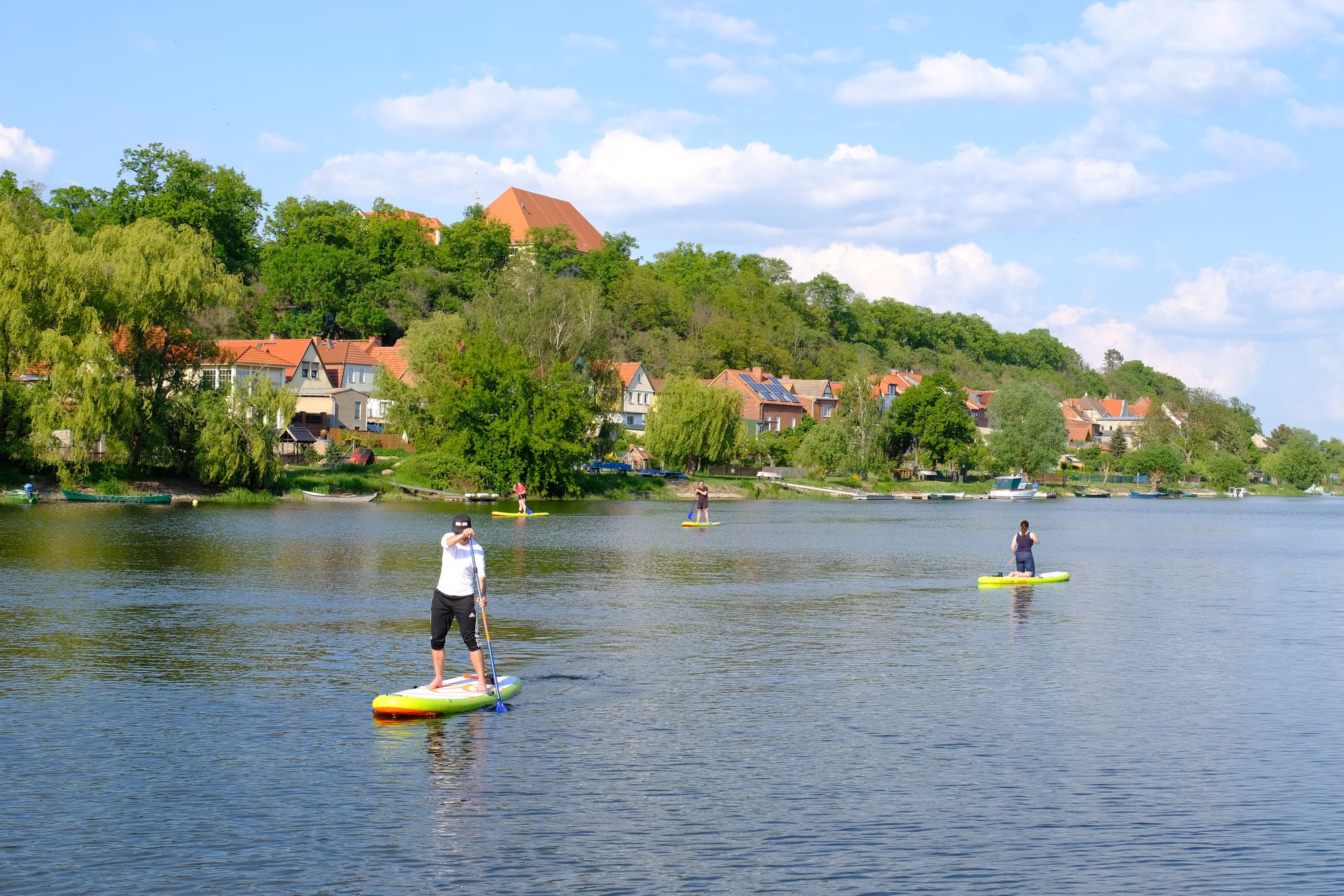 Stand-up-Paddler auf der Havel vor Havelberg mit Dom und Uferhäusern