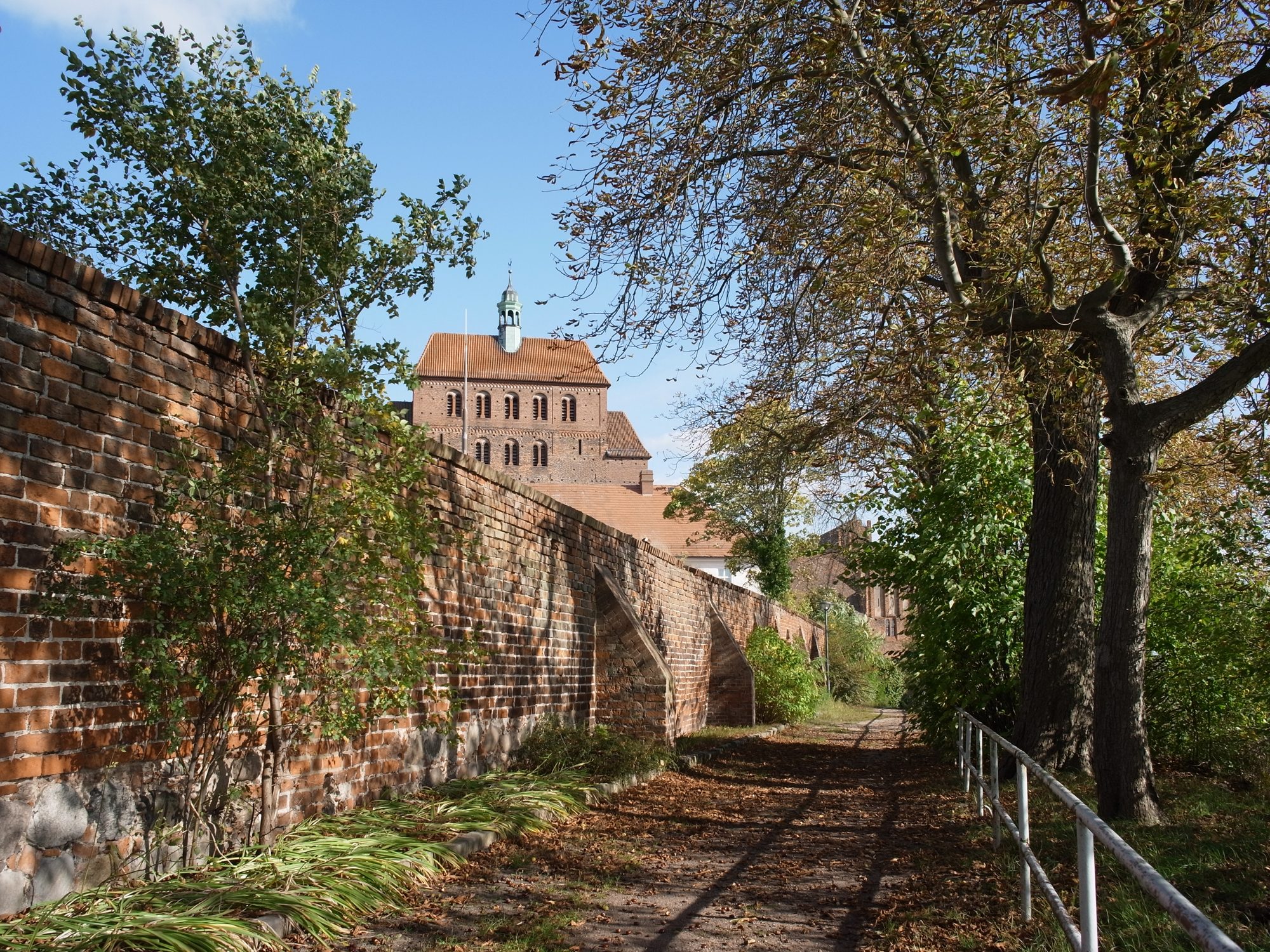 Herbstlicher Weg entlang der historischen Backstein-Stadtmauer von Havelberg mit Blick auf den Dom im Hintergrund